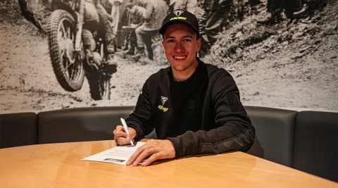 Jeremy Sydow sat at a table signing a contract from Triumph EnduroGP