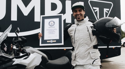 Iván Cervantes stood next to his Triumph Tiger 1200 GT Explorer holding his Guinness World Records Certificate