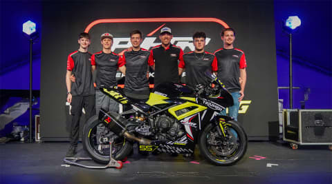 Right hand side of Triumph Daytona 660 with people standing behind it