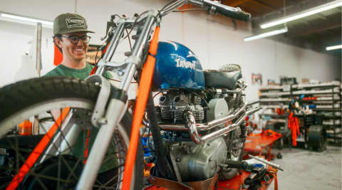 Elliot Delapré Owner of Le hanger 23 behind Triumph Blue Bike