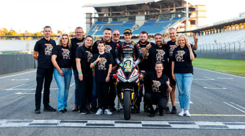 Group of people surrounding a racer on Triumph Daytona 660