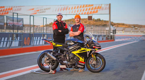 Two people stood behind Triumph Street Triple 765 RS on race track