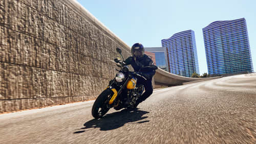 Triumph Trident 660 in cosmic yellow and sapphire black in urban setting cornering
