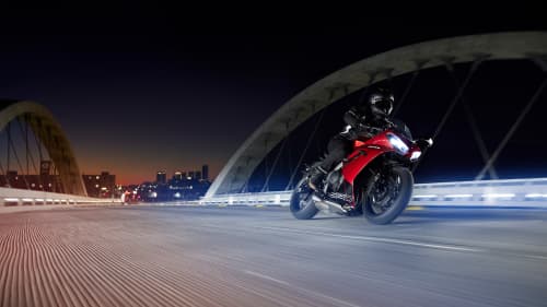 Triumph Daytona 600 in Carnival Red & Sapphire Black riding over bridge at night