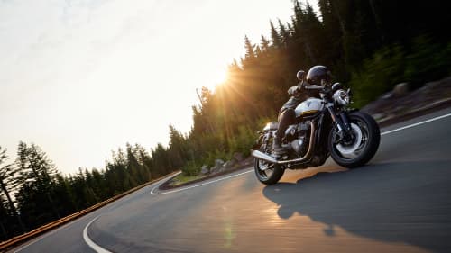 Man riding on Triumph Speed Twin 1200 on a road with a forest in the background
