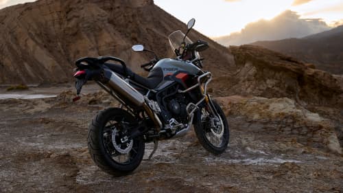 Angled rear side view of Triumph Tiger 900 Desert Edition parked on a rocky hill