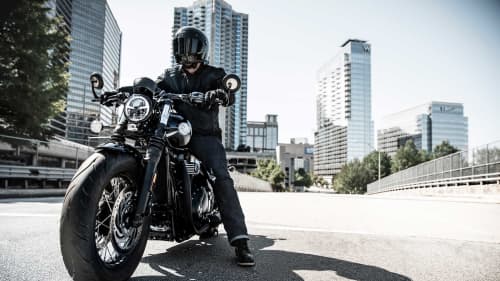 TRIUMPH BOBBER BLACK MOTORCYCLE WITH RIDER ON MIAMI HIGHWAY