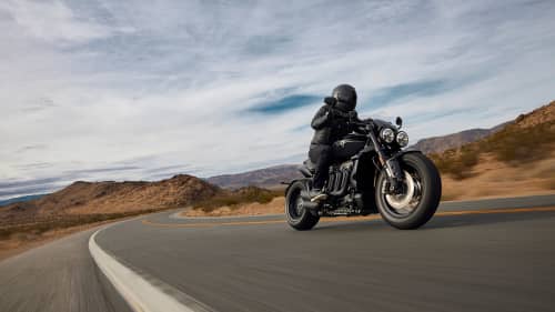 Person riding Triumph Rocket 3 R Storm through roads with dry surroundings