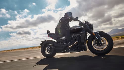 Close up of a person riding Triumph Rocket 3 GT Storm with cloudy skies in the back