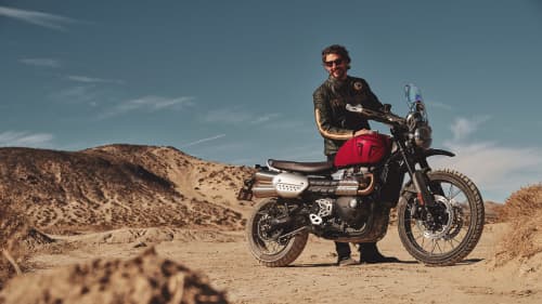 Rider stood behind a Triumph Scrambler 1200 X in carnival red