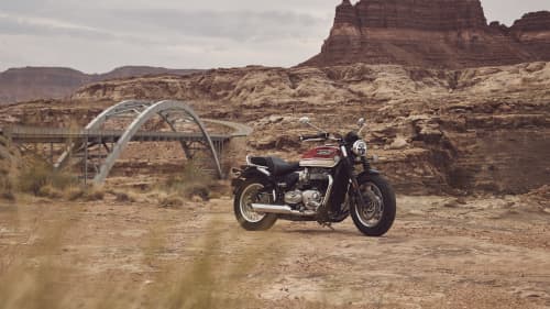 Triumph Bonneville Speedmaster on dusty terrain and mountains in the background