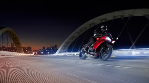 Triumph Daytona 600 in Carnival Red & Sapphire Black riding over bridge at night