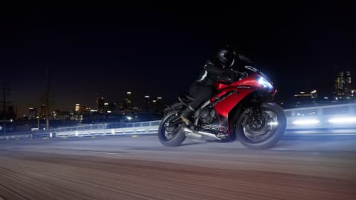 Triumph Daytona 660 in carnival red and sapphire through city at night