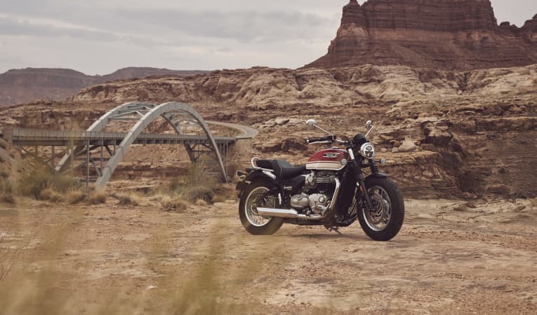 Triumph Bonneville Speedmaster on dusty terrain and mountains in the background