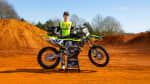 Austin Forkner standing behind TF 450-X on dusty terrain