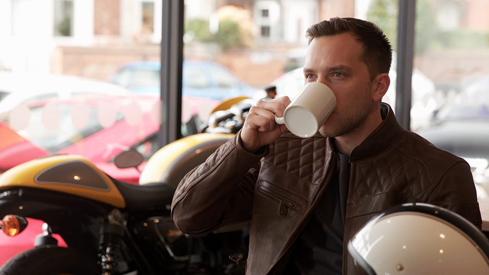 Man drinking coffee in Triumph dealership