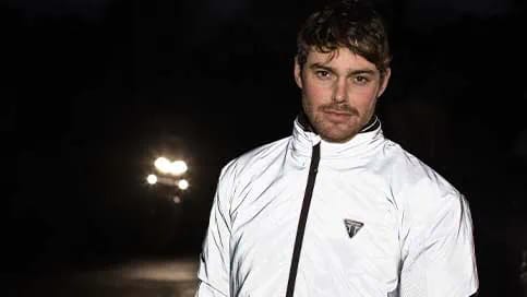 A man wearing a Triumph high visibility jacket at night