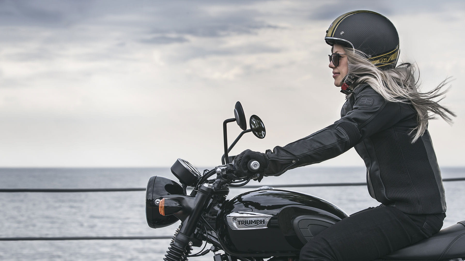 Female rider on a Triumph Motorcycle with water in the background