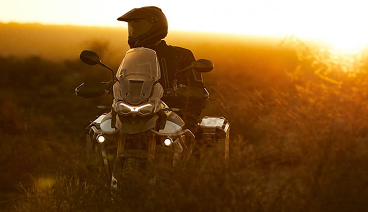 Tiger 900 with panniers off-road with orange sun glow