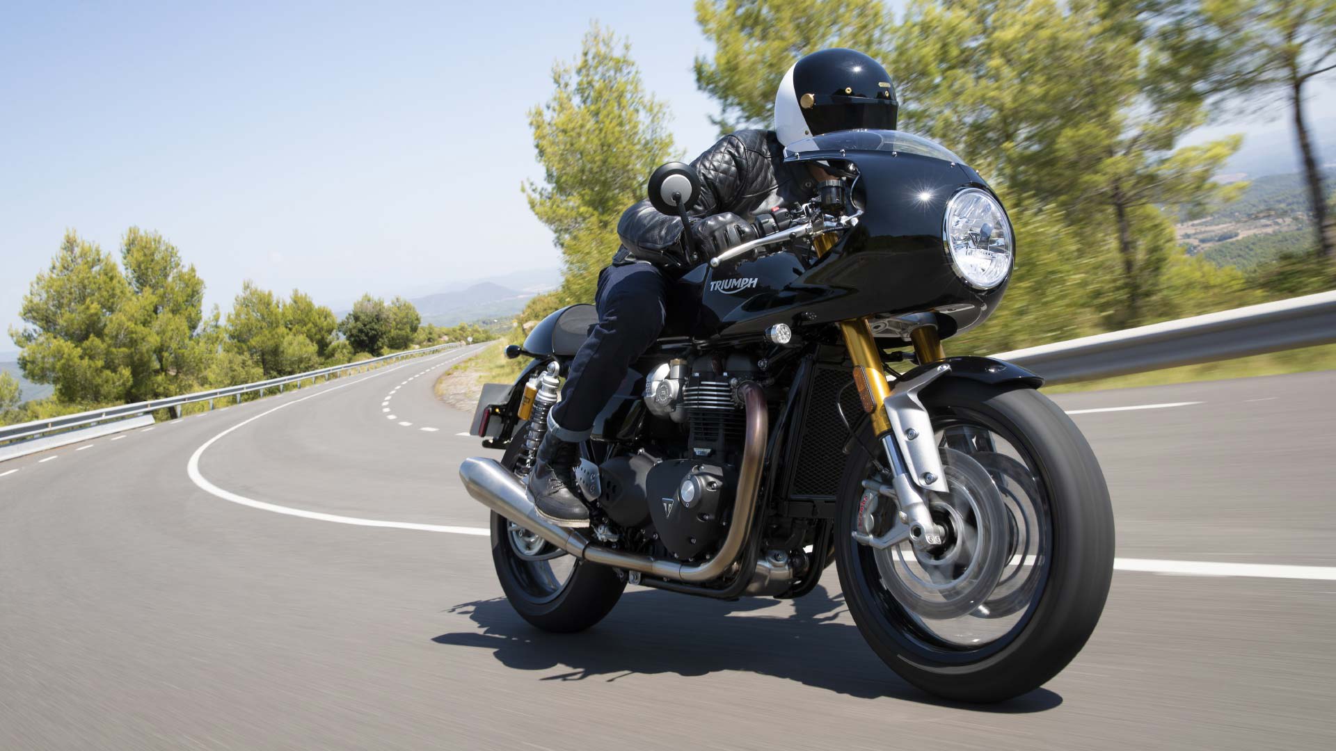 Action shot of the new Triumph Thruxton RS in Jet Black with fairing accelerating through scenic views