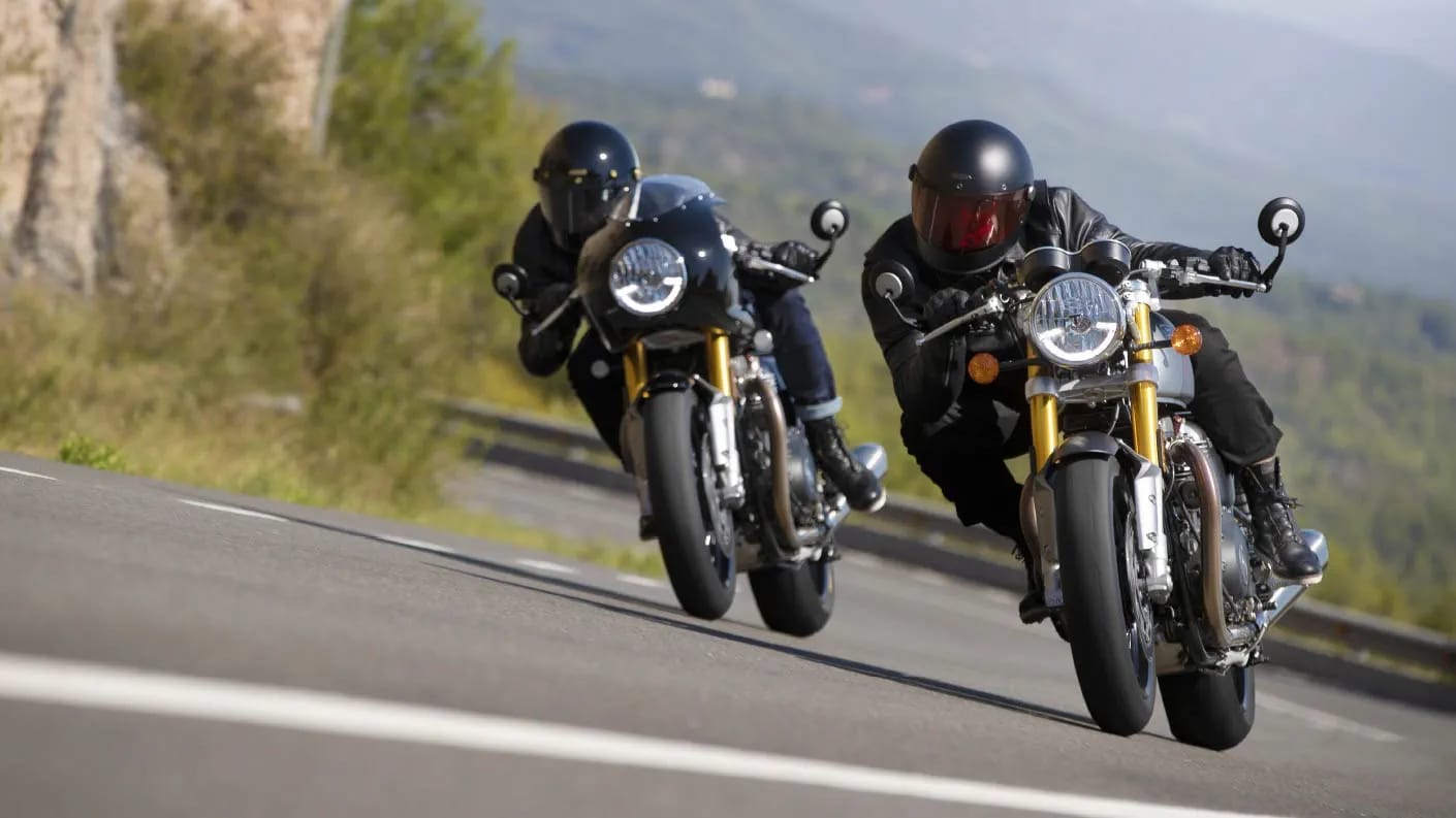 Action shot of two new Triumph Thruxton RS motorcycles cornering through mountainous roads 