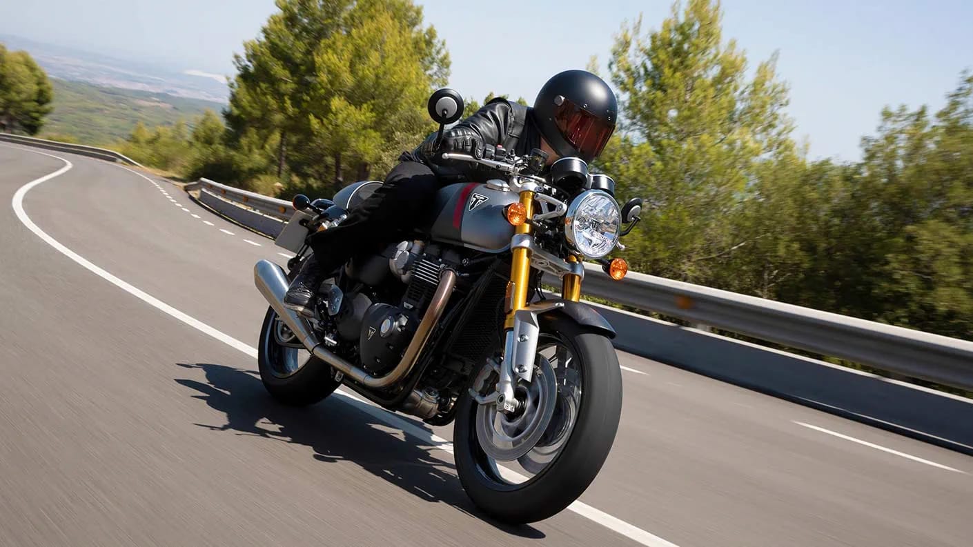 Action shot of Triumph Thruxton RS in Matt Storm Grey & Matt Silver Ice accelerating down mountainous road 