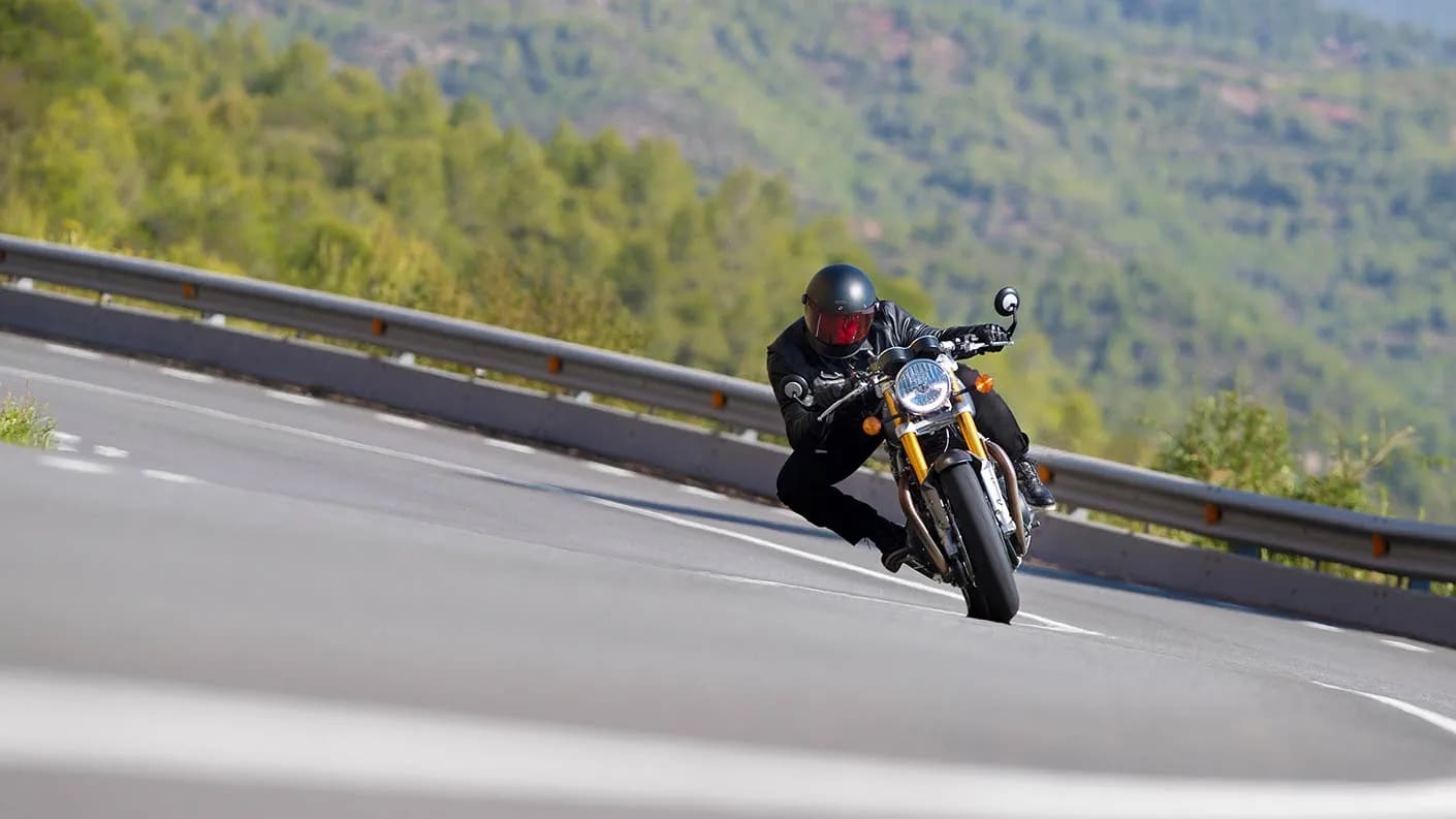 Action shot of rider cornering through mountainous roads on the new Triumph Thruxton RS