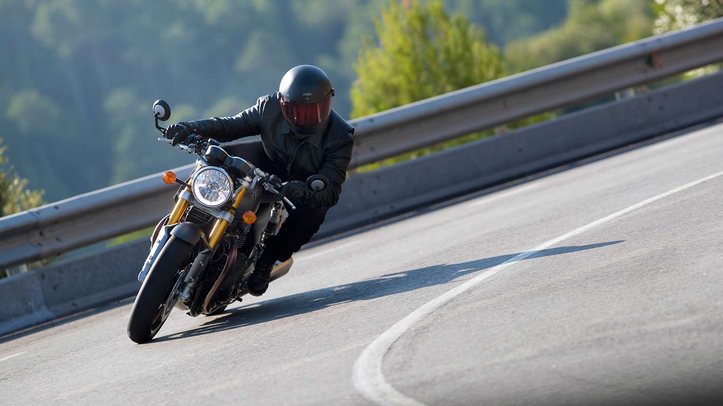 Action shot of rider cornering through mountainous roads on the new Triumph Thruxton RS