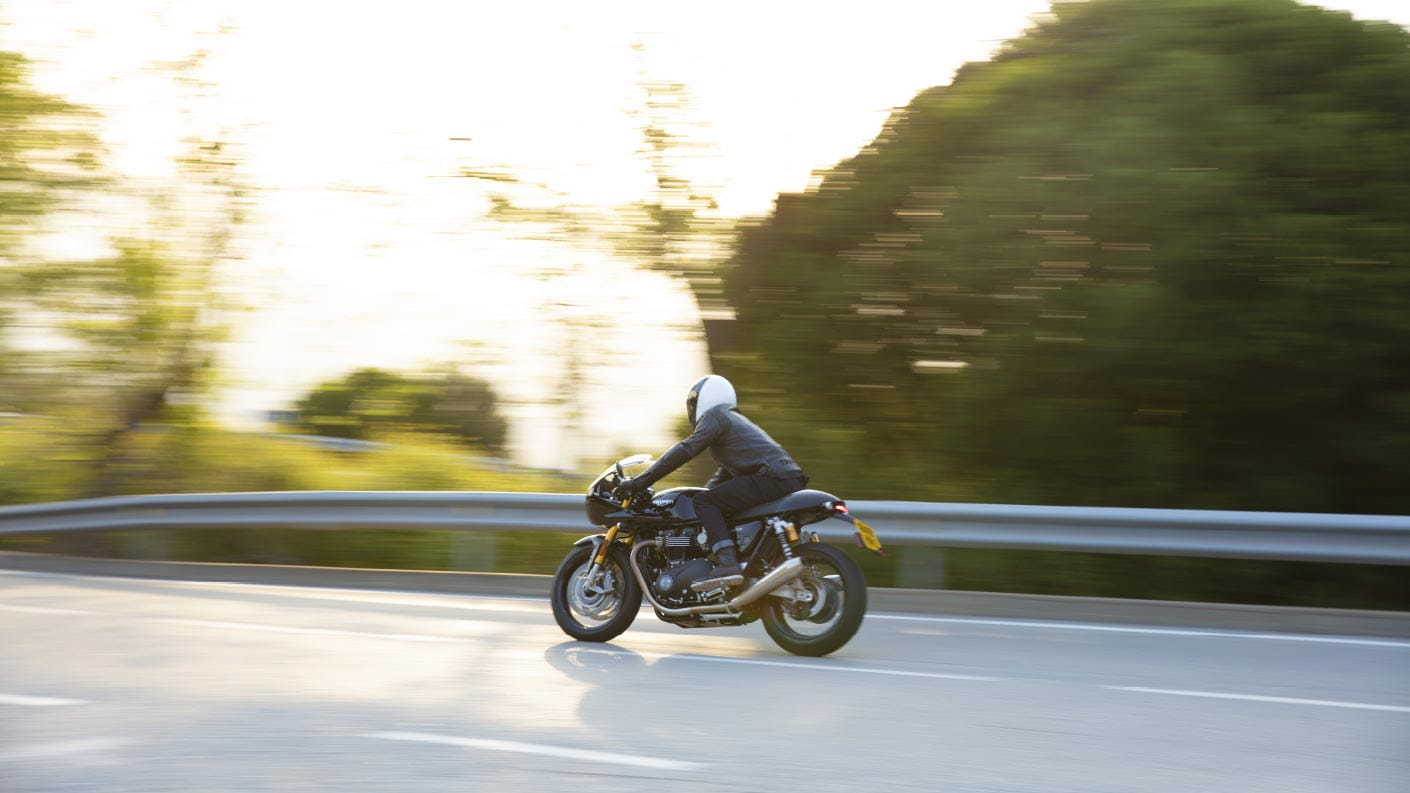 Action shot of the new Triumph Thruxton RS with fairing in Jet Black riding down a mountainous road