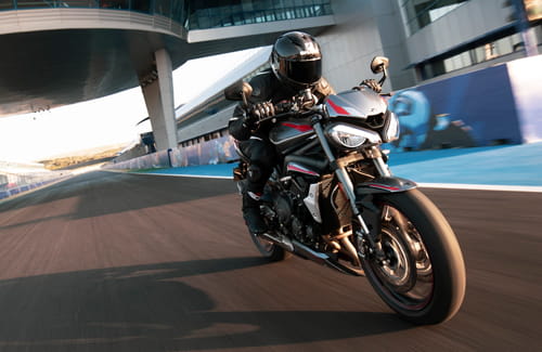 Rider on new Triumph Street Triple RS in Silver Ice powering down a racetrack straight