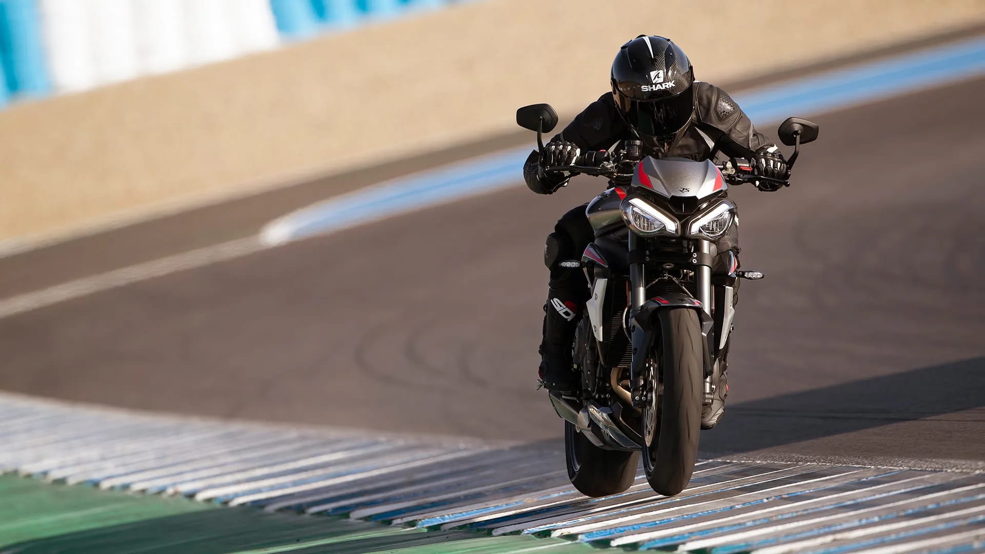 Action shot of rider on new Triumph Street Triple RS in Silver Ice powering down a racetrack