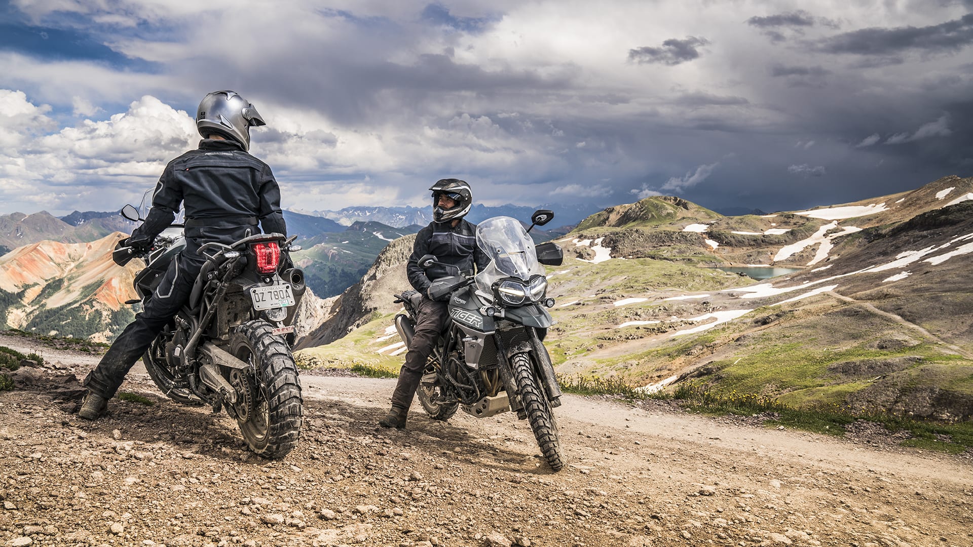 Two riders on Triumph Tiger 800s riding in mountainous scenery on gravel roads