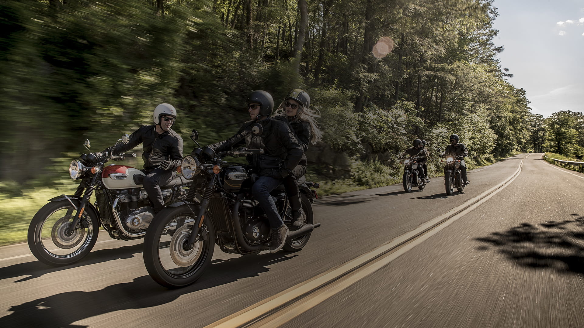 Group of people riding T100s through the country side. 