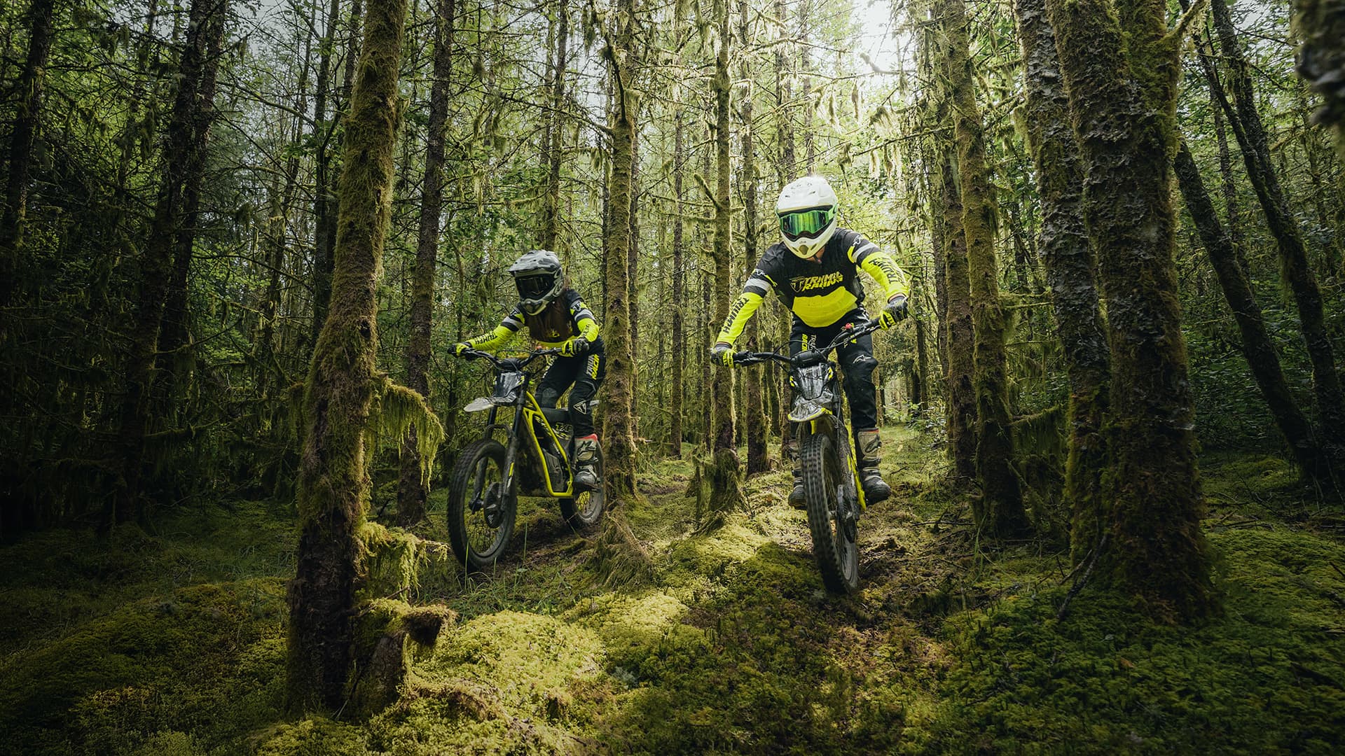 Young riders on Triumph Oset bikes riding through a forest