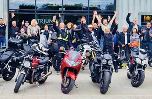 Triumph Factory Visitor Experience bikes and a crowd standing outside the building