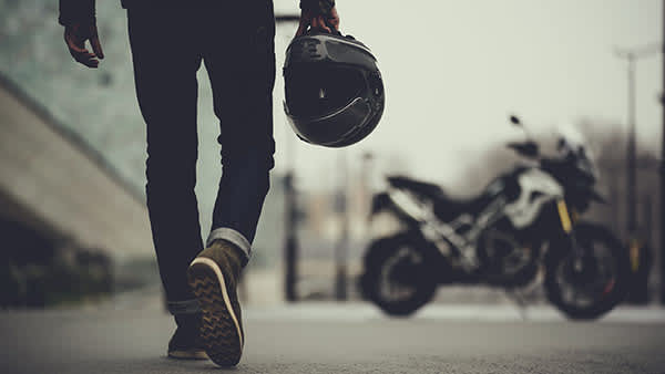 Person approaching a Triumph Tiger 1200 with motorcycle helmet
