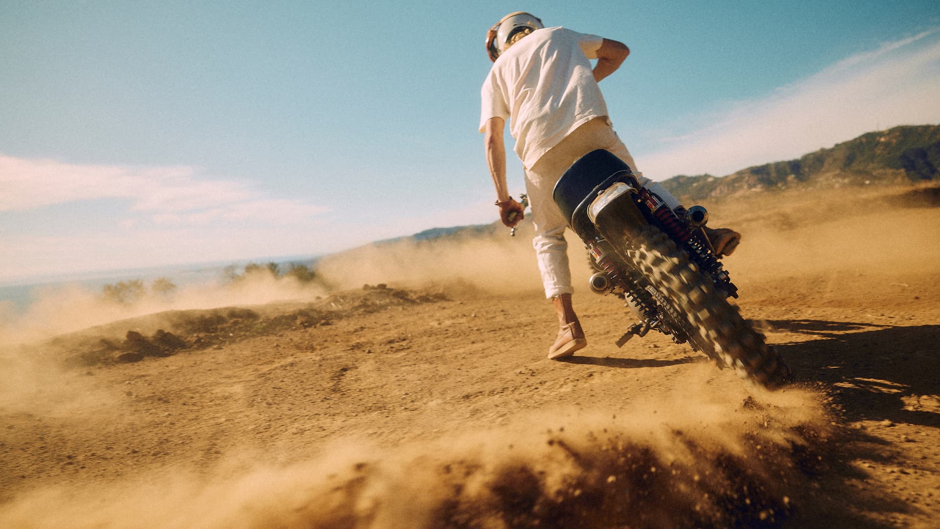 Man on a Triumph TR6 in the sand drifting