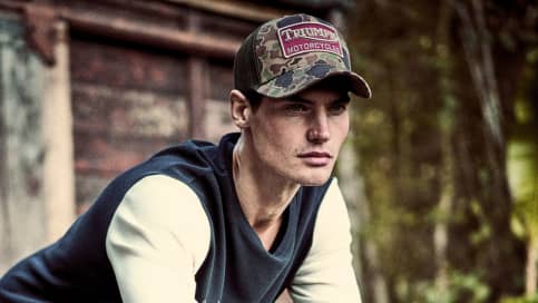 Close up of man leaning on fence with Triumph Lifestyle Trucker Caps
