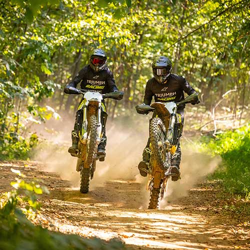 Triumph Cross Country motorcycles riding through a forest