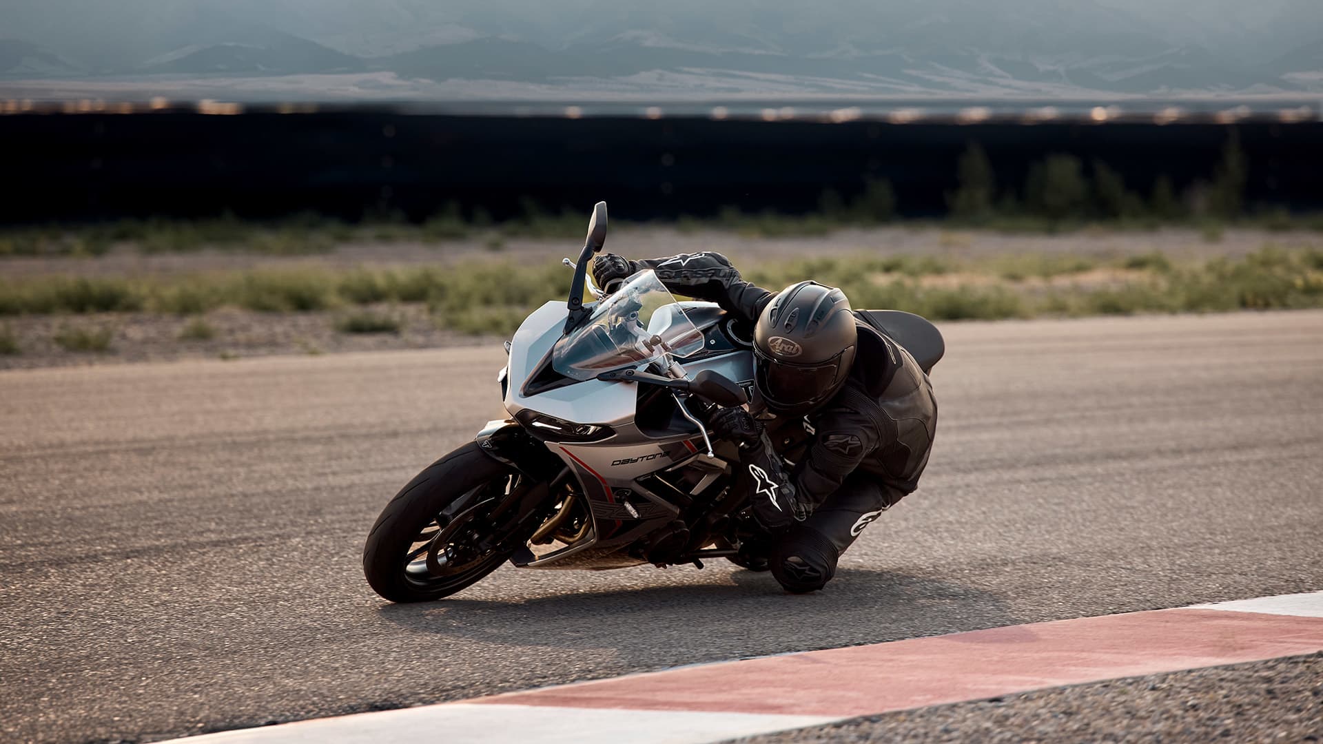 Angled side view riding shot of Triumph Daytona 660 in Aluminium Silver on a race track