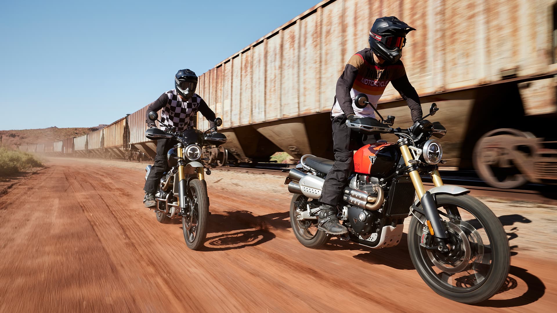 Triumph Scrambler 1200 XE riding on sand next to train