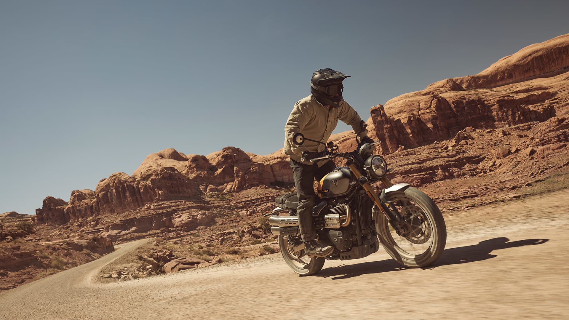 Rider on Triumph Scrambler 900 riding through dusty terrain