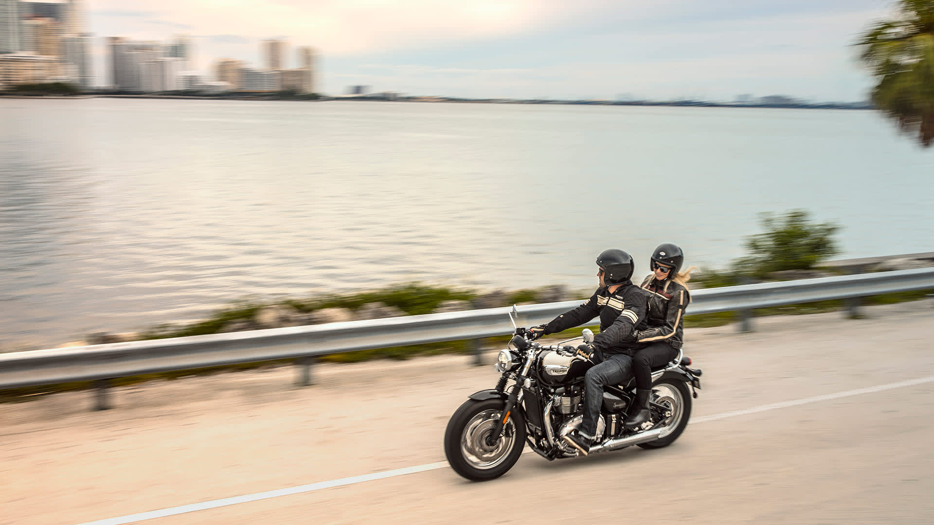 Triumph Speedmaster with rider and pillion riding along Miami coast