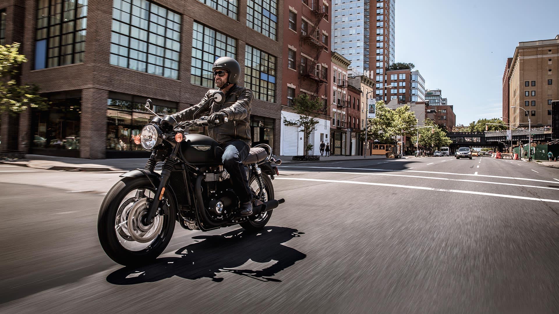 Triumph bonneville T120 black riding through city
