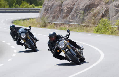 Action shot of two new Triumph Thruxton RS motorcycles flowing through mountainous corners