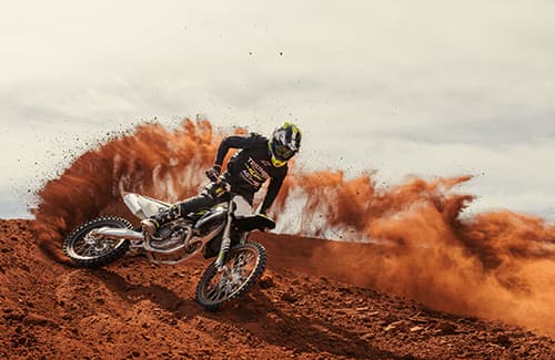 Motocross rider cornering on motocross track riding a Triumph TF 250-X