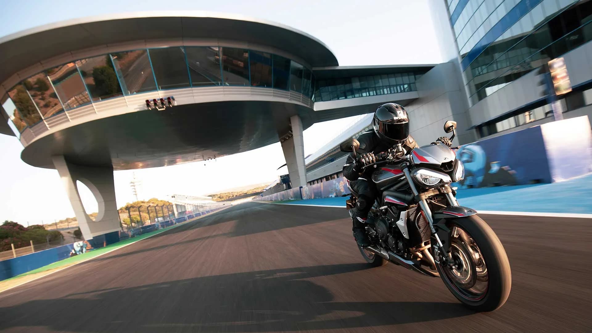 Rider on new Triumph Street Triple RS in Silver Ice powering down a racetrack straight