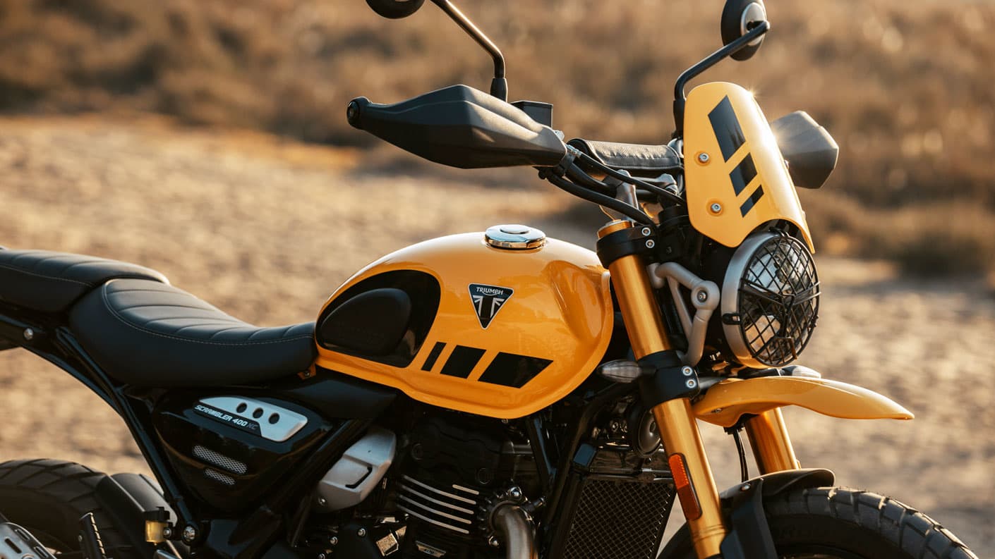 A close up shot of a Racing Yellow Triumph Scrambler 400 XC, showing Tank and Fly screen detail