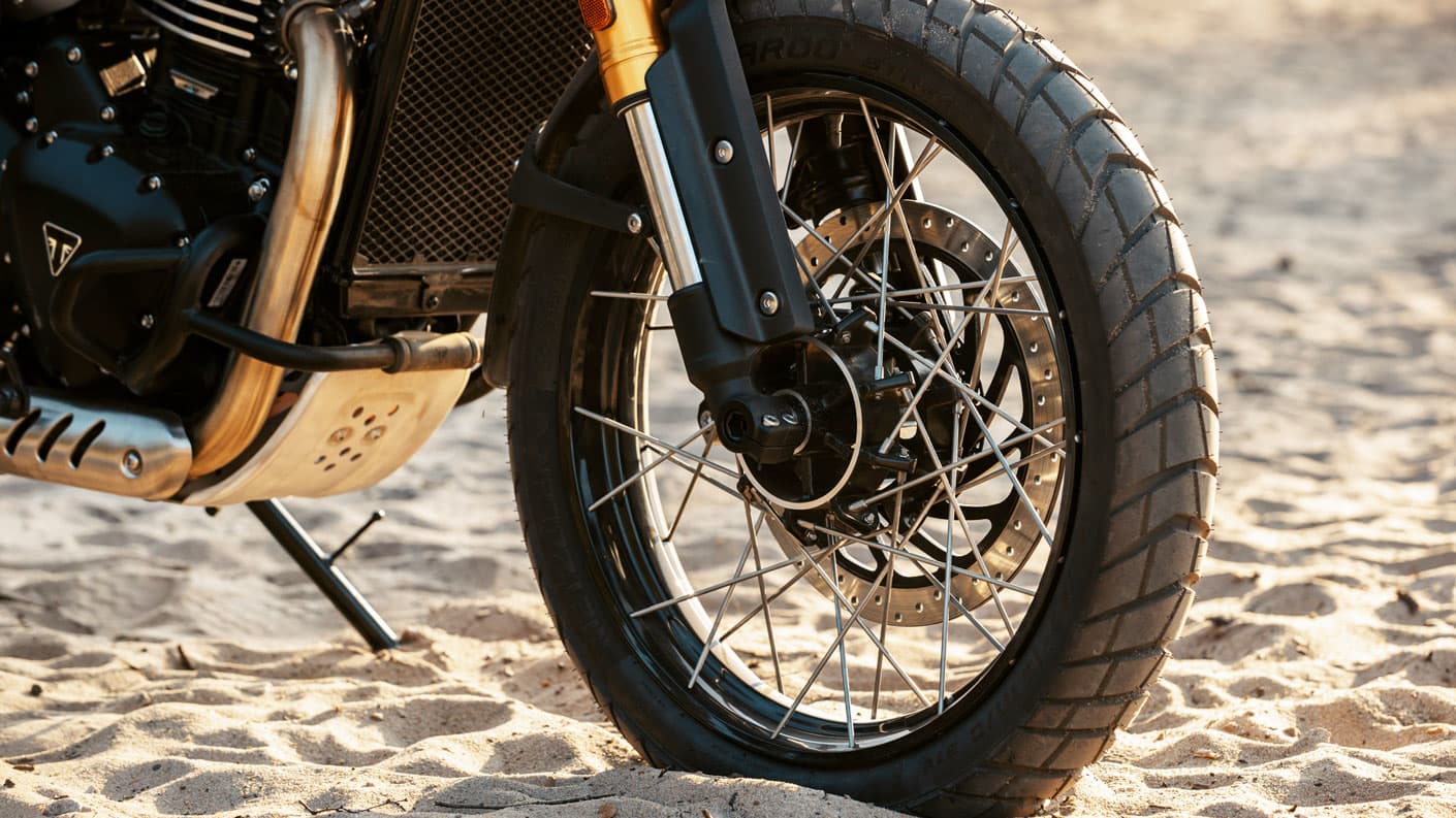 A close up shot of a Triumph Scrambler 400 XC's spoked front wheel