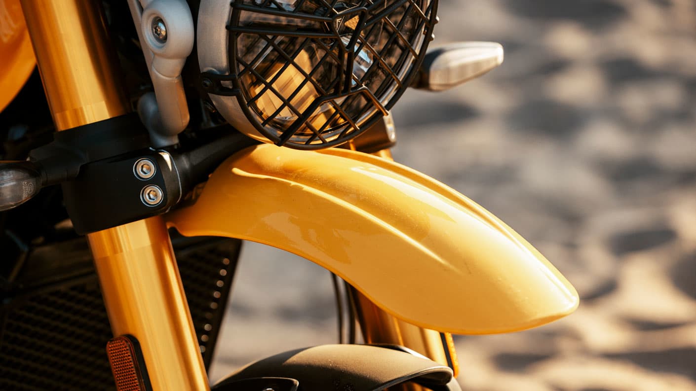 A close up of high-level front mudguard on a Racing Yellow Triumph Scrambler 400 XC